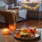 Podnos s čajom a dekoráciami pri sviečkach, v pozadí sedačka a zažaté svetielka.