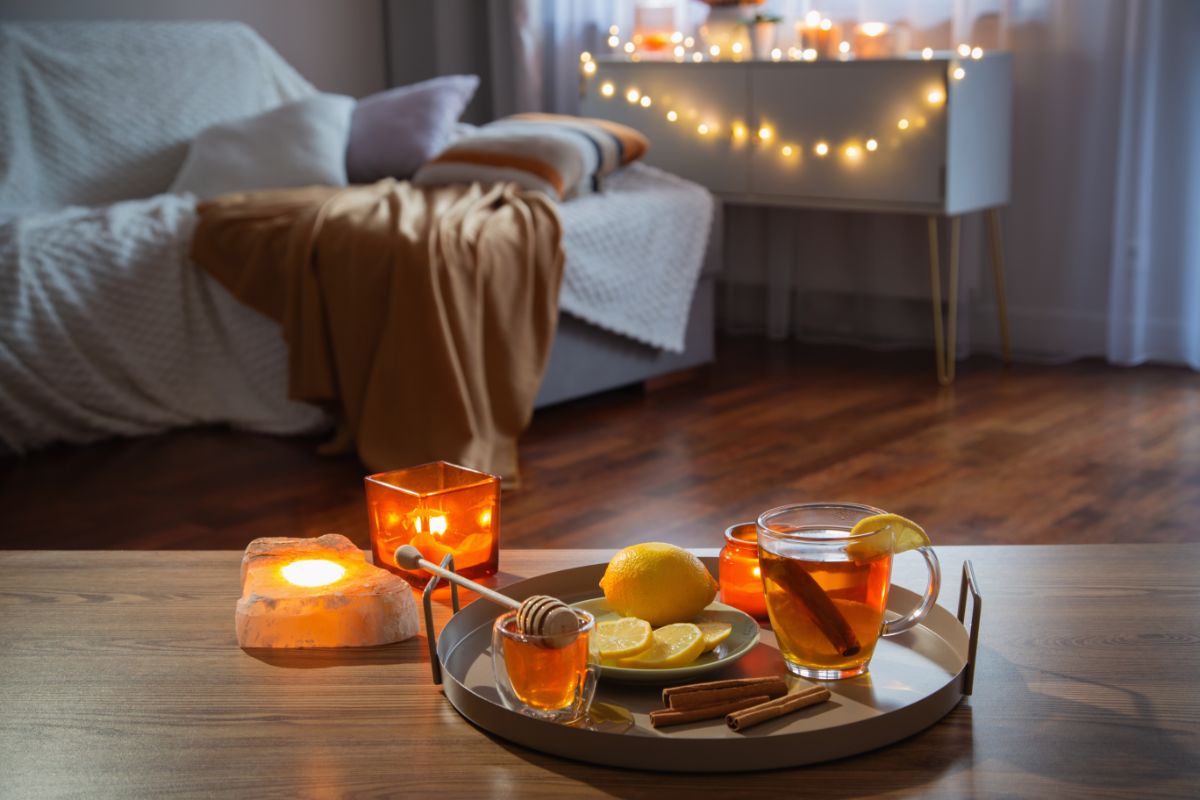 Podnos s čajom a dekoráciami pri sviečkach, v pozadí sedačka a zažaté svetielka.