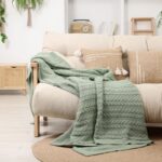 Zelená deka na svetlom komfortnom gauči.