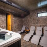 Oddychová miestnosť s vírivkou a štyrmi ležadlami, tmavým mramorovým obkladom a malým oknom.