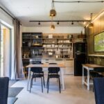 Moderný apartmán s drevenou kuchyňou, otvorenými policami a dreveným obkladom.