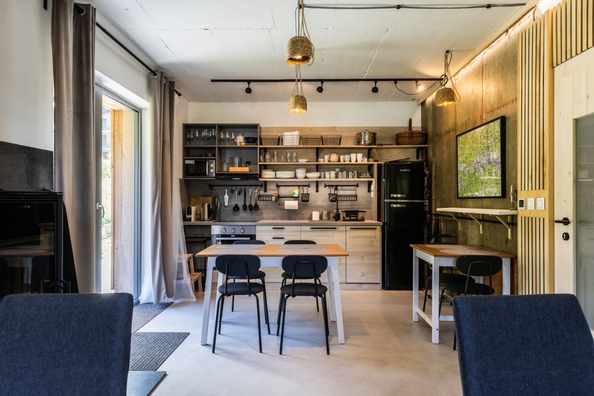 Moderný apartmán s drevenou kuchyňou, otvorenými policami a dreveným obkladom.