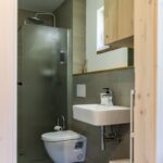 Malá moderná kúpeľňa s tmavosivými obkladmi, bielym umývadlom a WC.