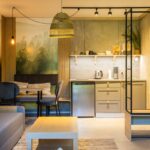 Otvorená dispozícia s kuchynským kútom, pohovkou a jedálenským kútom pri fototapete lesa.