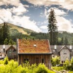 Chata s dreveným obkladom a zelenou vegetačnou strechou uprostred horského strediska.