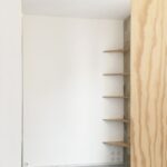 Rohové police z preglejky v prázdnom priestore.