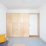 Vstup do bytu lemovaný drevenými skriňami, sedačka so žltým vankúšom.