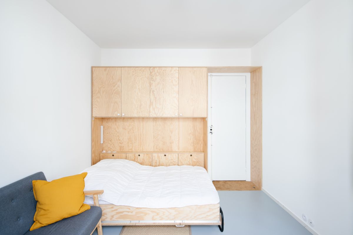 Vstup do bytu lemovaný drevenými skriňami, sedačka so žltým vankúšom.