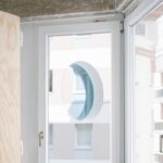 Odraz okrúhleho priehľadu v okne v byte.