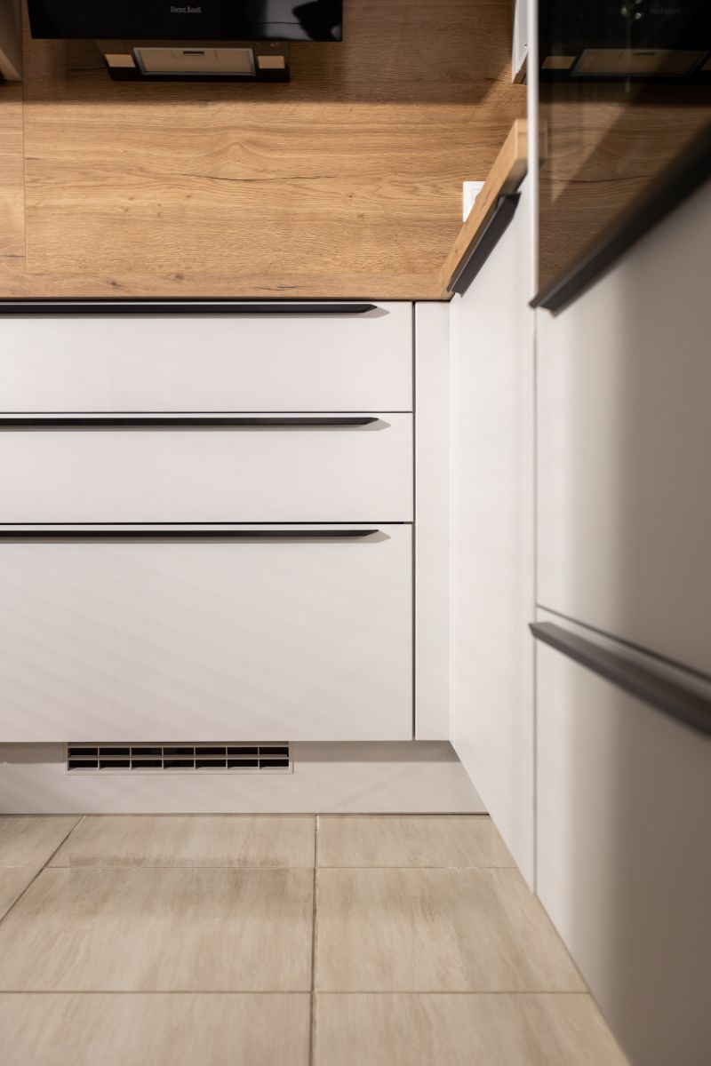 Spodné biele kuchynské zásuvky s čiernymi úchytkami.