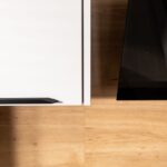 Hrana bielej kuchynskej skrinky s čiernym úchytkom v kontraste s drevenou plochou a čiernym panelom.