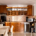 Staršia drevená kuchynská linka s hnedým dekorom dubu a béžovým keramickým obkladom v klasickom interiéri.