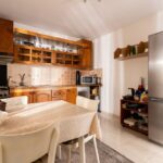 Kombinácia hnedej kuchynskej linky s nerezovými spotrebičmi a voľne stojacou chladničkou.