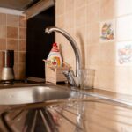 Antikorový kuchynský drez s chrómovou batériou v tmavej pracovnej doske.