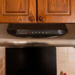 digestor s ovládacími tlačidlami pod hnedou drevenou skrinkou.