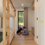 etská izba so svetlými drevenými poschodovými posteľami a drevenou podlahou.