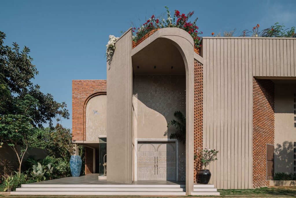 Moderná béžová fasáda s tehlovým obkladom, výrazným betónovým oblúkom a bohatou strešnou zeleňou.