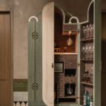 Otvorený zelený barový kabinet s dreveným interiérom, zrkadlom a sklenenými policami.