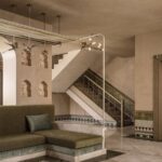 Zelená rohová pohovka pri schodisku s kamenným obkladom a dekoratívnymi výklenkami v stene.