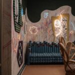 Modrá valcovitá pohovka pred stenou s graffiti a neónovými svetelnými dekoráciami.