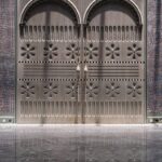 Sivé drevené dvojkrídlové dvere s vyrezávaným kvetinovým motívom a lineárnym frézovaním na textilnom pozadí.