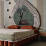 Moderná kúpeľňa s terakotovým umývadlom, oválnym zrkadlom a drobným keramickým obkladom v zemitých tónoch.