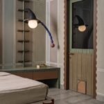 Zelený barový kabinet s dreveným interiérom, zrkadlovou stenou a mosadznými detailmi v jedálenskom kúte.