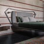 Posteľ s kovovým a čalúneným čelom, dekoratívnym obkladom a samonosným stolíkom.