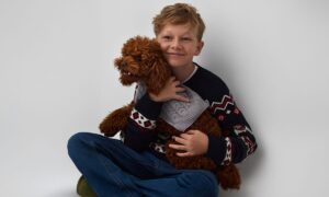 Malý chlapec držiaci psa s pleteným svetrom.