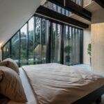 Pohľad cez posteľ vo výklenku pri presklených posuvných dverách.