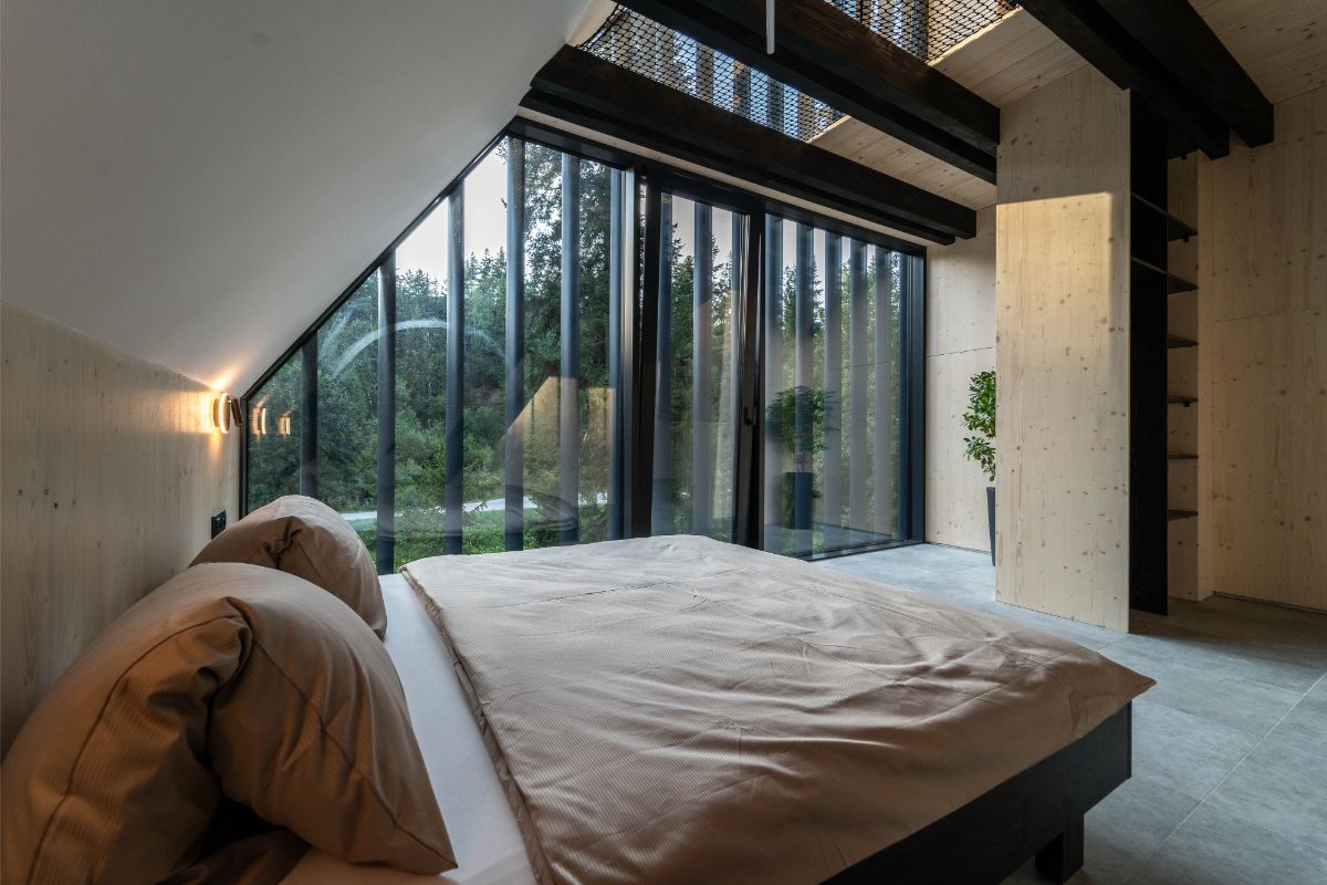 Pohľad cez posteľ vo výklenku pri presklených posuvných dverách.