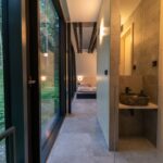 Svetlá drevená chodba s kamenným umývadlom na pulte, sivou dlažbou a čiernymi prvkami.