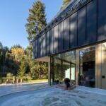 Vonkajšia vírivka na terase pri chate s čiernym plechovým obkladom a sklenenými posuvnými dverami.