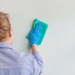 Žena čistí handrou stenu.