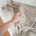 Detail na mužskú ruku berúci si uterák z radiátora.