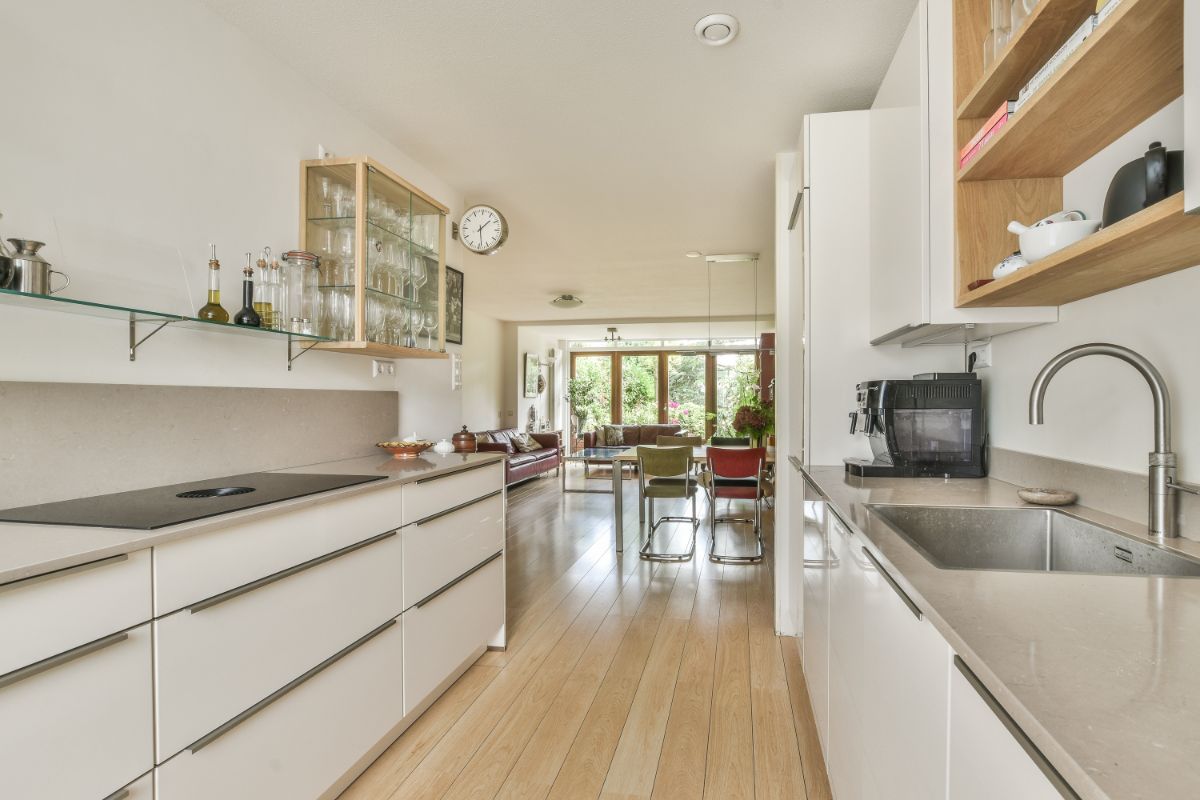 Biela moderná linka spojená s obývačkou a jedálňou s drevenou podlahou bez kobercov.