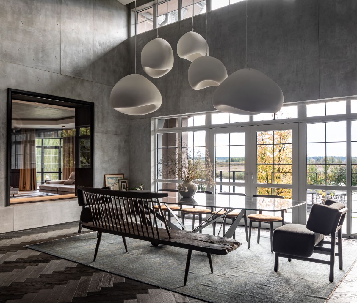 Veľkú miestnosť s vysokými stropmi a betónovými múrmi spríjemňuje presklenie s dverami na terasu.