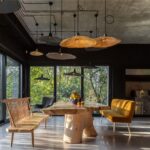 Priestranná jedáleň s masívnym dreveným stolom, žltou zamatovou lavicou a kovovými lampami.