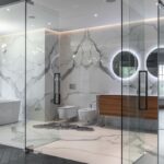 Luxusná kúpeľňa s bielym mramorovým obkladom, voľne stojacou vaňou a preskleným sprchovacím kútom.