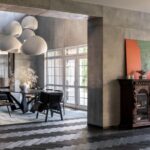 Jedáleň s betónovými stenami, tmavou podlahou a masívnou vyrezávanou drevenou komodou.