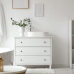 Biely interiér s bielizníkom, vaňou a policou.