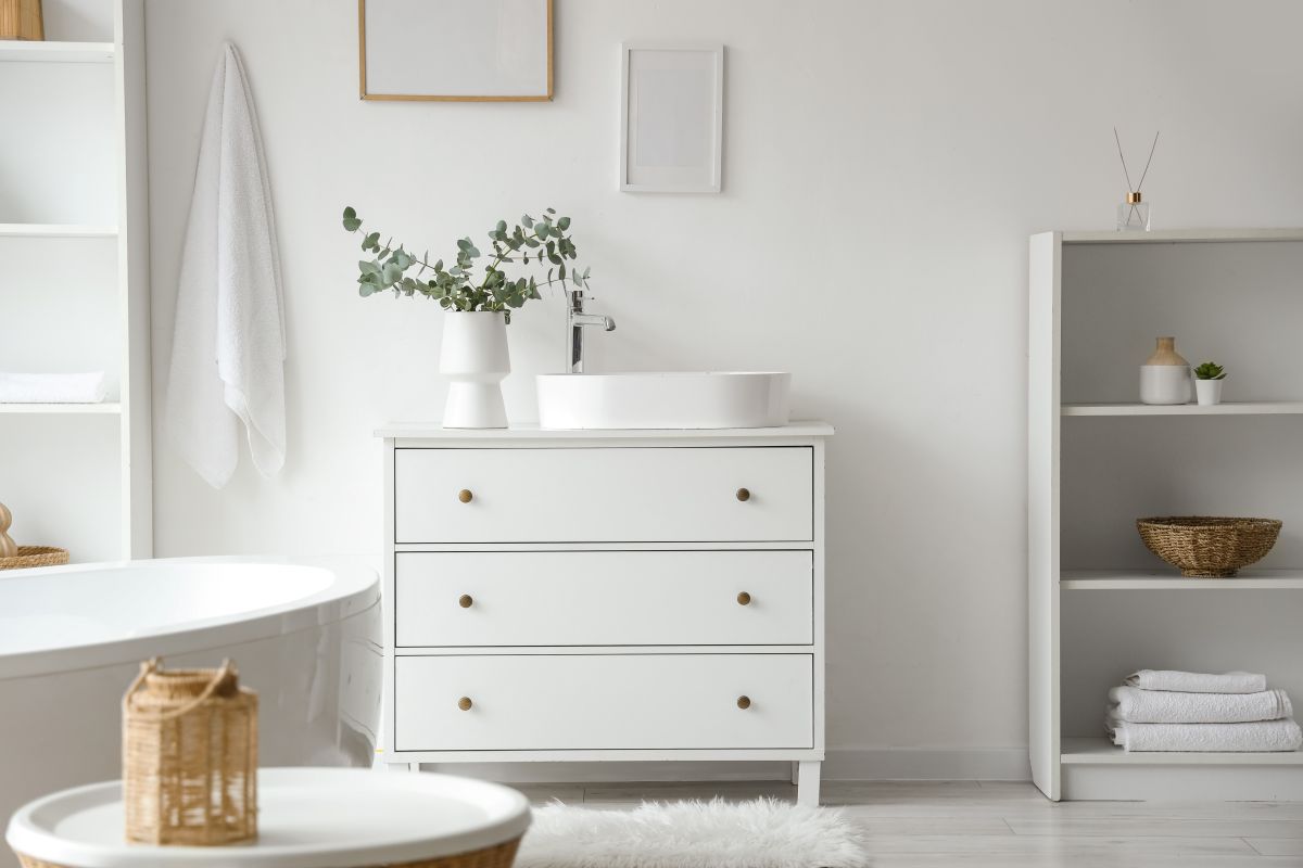 Biely interiér s bielizníkom, vaňou a policou.