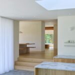 Pohľad z kuchyne na vyvýšené podlažie s dreveným stolom.