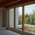 Výhľad zo spálne cez viacdielne okno s dreveným rámom.