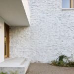 Pôvodné kamenné murivo s vápenným náterom v kontraste s hladkou omietkou a betónovým schodiskom pri vstupe.