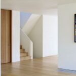 Svetlý interiér s dubovou podlahou a oblým bielym schodiskom s drevenými stupňami.