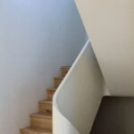 Schodisko s masívnymi dubovými stupňami a jednoliatym bielym zábradlím.