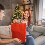 Mladý muž dáva darčekovú tašku mladej žene.