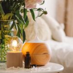 Aróma difuzér pri rastline a sviečke na nočnom stolíku.