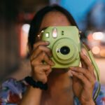 Detail ženy pri fotení instantným fotoaparátom.